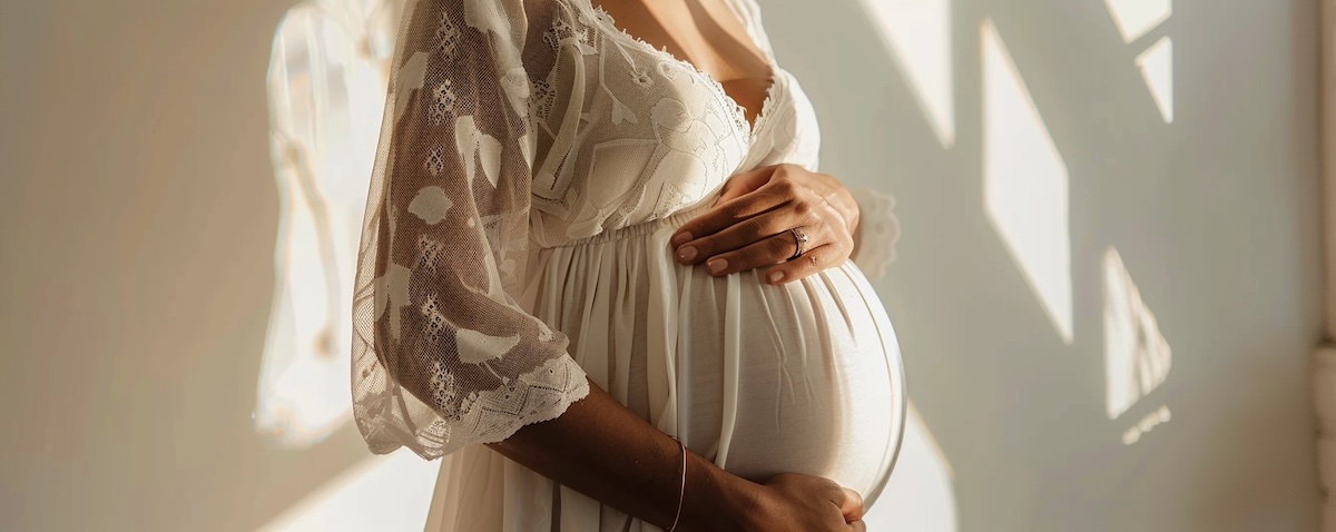 Schwangere Frau hält ihren Bauch, Bauchnabelpiercing sichtbar