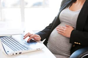 Schwangere Frau, die Arbeiten am laptop Schwanger am Arbeitsplatz