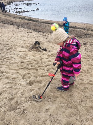 Kind mit Metalldetektor am Strand