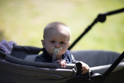 Baby im Kinderwagen mit Schnulerkette