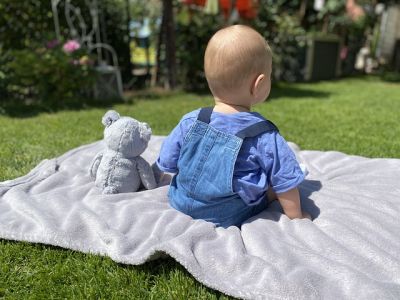 Krabbeldecke für den Garten - Baby sitzt auf einer Decke im garten