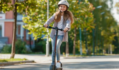 Mädchen fährt auf einem E-Scooter zur Schule