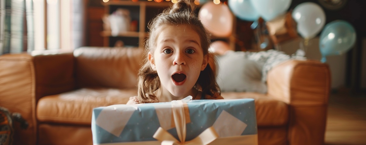 Achtjähriges Mädchen freut sich beim Auspacken eines Geschenks